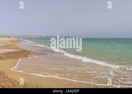Panoramic photo of the port of Valencia on Balearic sea from yellow sandy beach with rolling green waves Stock Photo
