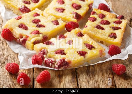Delicious sweet dessert custard pie with fresh raspberries close-up on parchment on the table. Horizontal Stock Photo