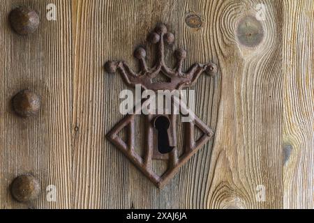 close-up flat photography of an old softwood textured door with ancient decorated rust metal keyhole and nail heads Stock Photo