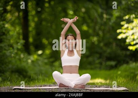 woman sitting in the lotus position, practicing meditation and yoga in the park Stock Photo