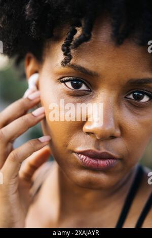 Close-up of a woman adjusting her wireless earphones. Portrait of a concentrated woman preparing for a workout. Stock Photo