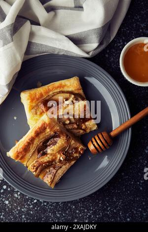 Fresh homemade pastries with pears and honey. Puff pastry tarts with pear slices, camembert, honey and walnuts top view. Stock Photo