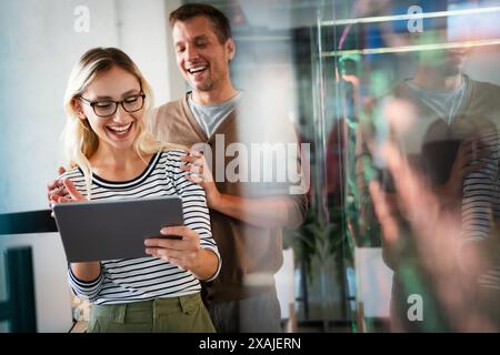 Two young businesspeople using a digital tablet while standing in a boardroom. Stock Photo