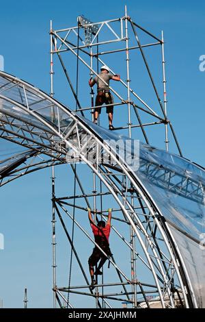 Craftsmen and workers working on a scaffolding at a stage set up for an event Stock Photo