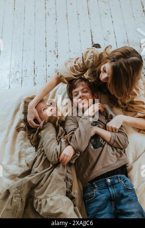 Woman tickling boy and a girl who are laughing Stock Photo