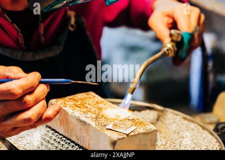 Close up of jewelers hands soldering with torch and flame Stock Photo