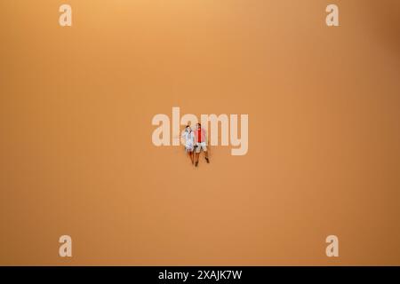 Couple lying down on a sand dune looking up aerial drone above view Stock Photo