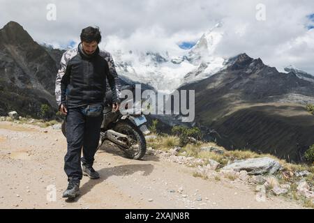 Man with an adventure motorcycle in front of a snowy mountain. Stock Photo