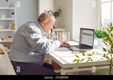 Elderly Man Working From Home With Computer Stock Photo