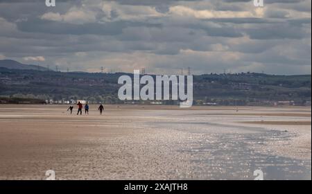 Aberlady, Scotland; 05/22/2021: A family of four walking on the beach in Aberlady during low tide, Scotland Stock Photo