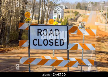 Road closed orange striped sign near an ongoing construction with blocking driving of cars Stock Photo