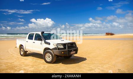 4WD trucks driving offroad on the Fraser island beach track near the SS Maheno shipwreck, half buried in the sand of the 75 mile beach on the east coa Stock Photo