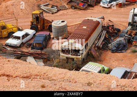 Old bus in a junkyard of rusty abandoned vintage cars in the desert of the Australian outback of the red center in the opal mining town of Coober Pedy Stock Photo