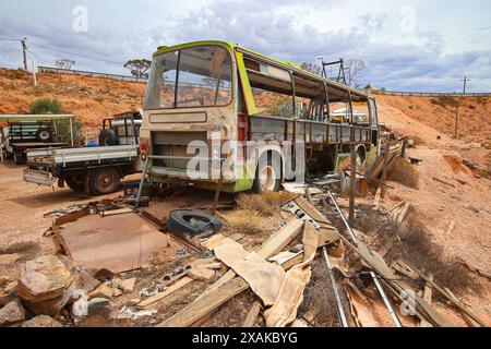 Old bus in a junkyard of rusty abandoned vintage cars in the desert of the Australian outback of the red center in the opal mining town of Coober Pedy Stock Photo