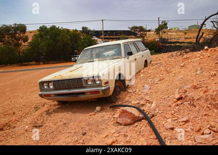 Junkyard of rusty abandoned vintage cars in the desert of the Australian outback of the red center in the opal mining town of Coober Pedy, South Austr Stock Photo