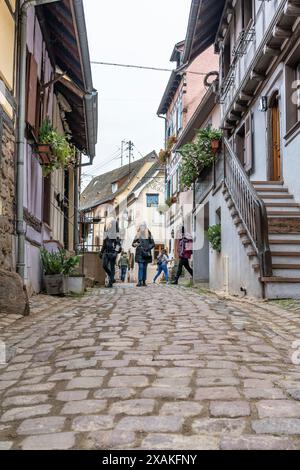 Europe, France, Grand Est, Alsace, Eguisheim, Tourists in a narrow cobblestone street Stock Photo