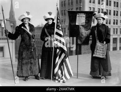 Suffragettes with flag, between c1910 and c1915. Shows women suffrage hikers General Rosalie Jones, Jessie Stubbs, and Colonel Ida Craft, who is wearing a bag labeled &quot;Votes for Women pilgrim leaflets&quot; and carrying a banner with a notice for a &quot;Woman Suffrage Party. Mass meeting. Opera House. Brooklyn Academy of Music. January 9th at 8:15 p.m.&quot; with speakers Rev. Anna Shaw, Mrs. Carrie Chapman Catt, and Max Eastman. Stock Photo