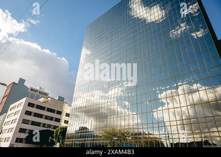 Mart South building next to a glass facade highrise reflecting clouds, Fashion District, Los Angeles, California, USA Stock Photo