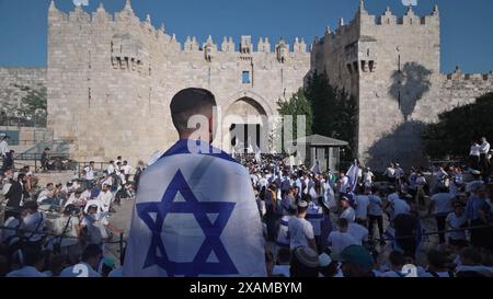 JERUSALEM- JUNE 5: Ultra-nationalist Israelis dance with Israeli flags outside Damascus Gate during the Jewish nationalist 'Flag March' to mark 'Jerusalem Day' in the Old City on June 5, 2024 in Jerusalem. Israel. The annual Jerusalem Day flag march typically draws thousands of nationalist Israelis who parade through the city, including the Muslim Quarter of the Old City. Stock Photo