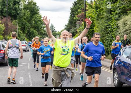 Leeds, UK. 07 JUN, 2024. Runner with arms raised looks at camera as runners complete 7 mile route, shaped like a rhino, through the streets of Moor town in honour of Leeds Rhinos legend number 7 Rob Burrow, who passed away on Sunday aged 41 following an over 4 year battle with motor neurone disease (MND). Credit Milo Chandler/Alamy Live News Stock Photo