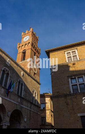 The Clock Tower on the town hall on the central piazza in the historic medieval town of Pienza in Tuscany, Italy on a sunny day with blue sky. Stock Photo