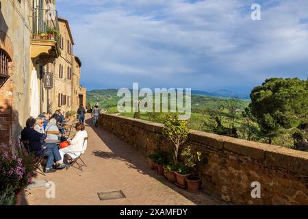 A classic scene at the famous viewpoint in Pienza in Tuscany, Italy on a sunny day with cloudy sky, with people sat outside a cafe bar drinking wine. Stock Photo