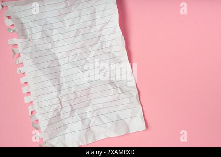 Wrinkled notebook sheet with stripes on pink background. Stock Photo