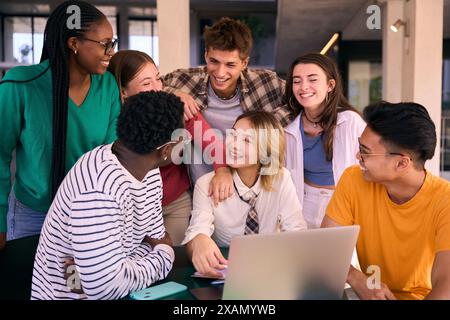 Group of young university students smiling using laptop computer at class room table on campus. Stock Photo