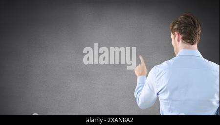Image of rear view of caucasian man touching invisible screen on grey background with copy space Stock Photo