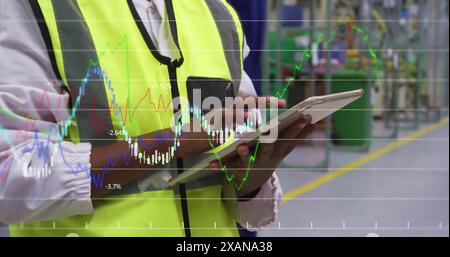Financial data processing against mid section of engineer using digital tablet at factory Stock Photo