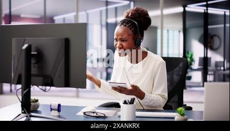 Worried African American businesswoman in office uses headset for video conference, stressed about cyber attack and data protection. Stock Photo