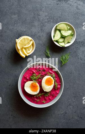 Cold summer beet soup with cucumbers, dill and egg  in bowl on blue stone background. Top view, flat lay Stock Photo