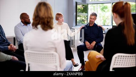 People Consoling Man In Group Therapy Session Stock Photo