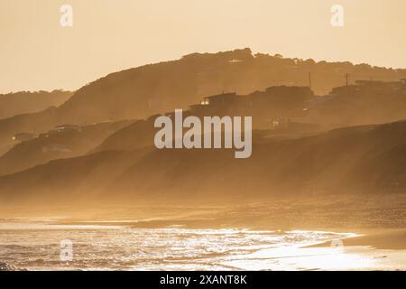 Distant view sea mist covering a hilly coastline in golden light at Fairhaven on the The Great Ocean Road in Victoria, Australia Stock Photo