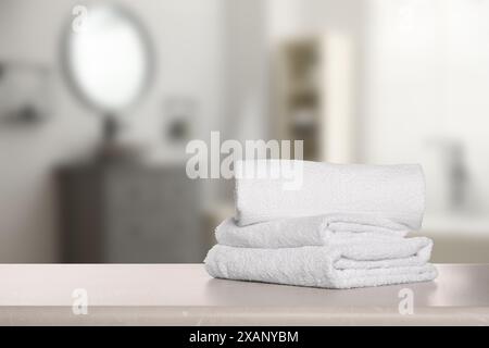 Folded fresh towels on table in bathroom. Space for text Stock Photo