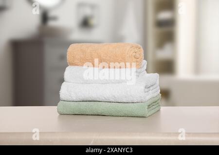 Folded fresh towels on table against blurred bathroom interior Stock Photo