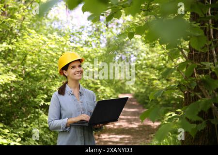 Forester with laptop examining plants in forest Stock Photo