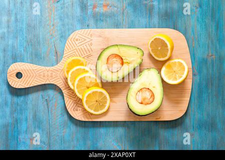 Lemon and avocado, fresh fruit on wooden board, healthy food concept Stock Photo