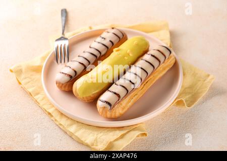 Different tasty glazed eclairs served on color textured table, closeup Stock Photo