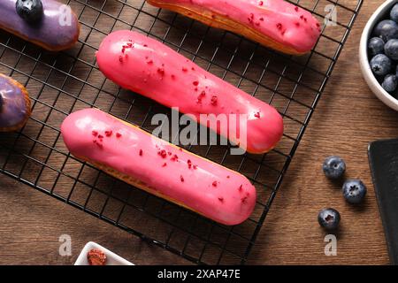 Tasty glazed eclairs and blueberries on wooden table, flat lay Stock Photo