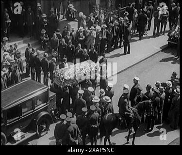 The Coffin of Rudolph Valentino Being Carried Into Malachy's Church Actor's Chapel as a Large Crowd of People Watch, 1926. ''He was the screen idol of millions - of just how many millions we were only to find out...when one day in 1926, unexpectedly, he died...and for untold numbers of the world's women, it was as though their own hearts had stopped...100,000 lined the route [of the funeral cortege]'. From &quot;Time to Remember 1926 - Short Sharp Shower&quot;- Reel 1; a documentary about 1926 - General Strike, international politics, dancing, weather and record breaking feats. Stock Photo