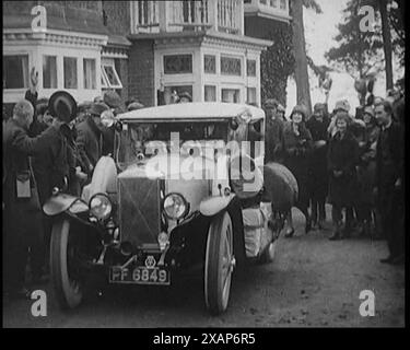 Two Female Civilians Explorers Driving Away in Their Heavily Loaded Car Watched by a Small Crowd, 1920s. From &quot;Time to Remember - Teenage Flapper&quot;, 1920s (Reel 4); a dcumentary about women's lives in the 1920s - great commentary by Joyce Grenfell. Stock Photo