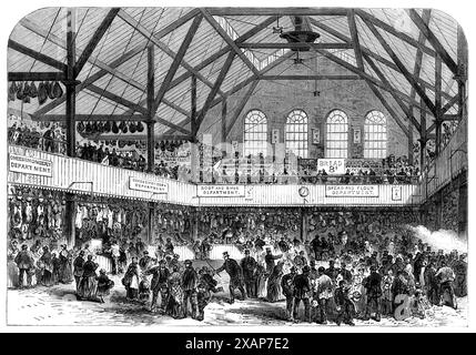 The People's Market, Whitechapel, [east London] 1868. '...the establishment, at 272, Whitechapel-road, opened...for the sale by retail, at moderate prices, of good meat, vegetables, and other necessary commodities, to the working-class population of that district...The market is lighted at night by two large sunlights, which serve the purposes at once of illumination and ventilation; and on each side of the building is a row of louvre windows, which may be opened in warm weather...the stalls or shops run round the building, one row upon the ground floor and the other in a gallery above; the ar Stock Photo