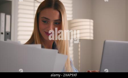 Caucasian woman student using laptop computer paperwork studying working home office online business girl businesswoman with papers documents check Stock Photo