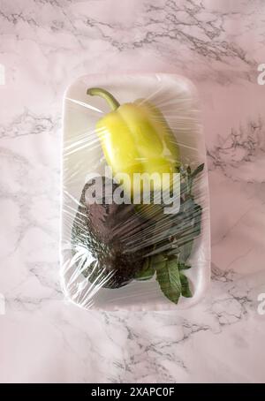 Green pepper, mentha and avocado packed in transparent plastic foil on kitchen table. Stock Photo