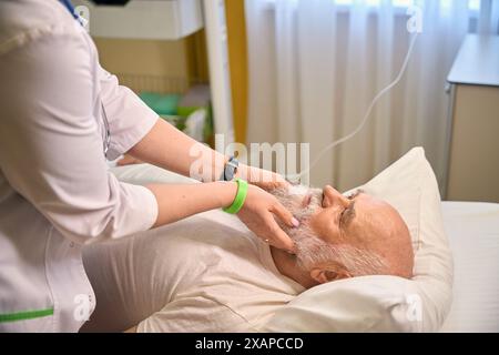 Doctor examining an old bald patient in a hospital room Stock Photo