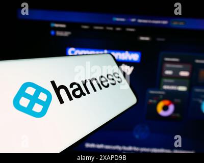 Cellphone with logo of American software delivery platform company Harness Inc. in front of website. Focus on center-left of phone display. Stock Photo
