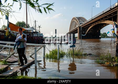 A man is seen carrying his little baby in a flooding area. The persistent rain in southern Germany is causing a rise in the water levels in the Dutch area close to Germany. d. At the Gelderland border town of Lobith, a level of 12.85 meters above NAP (the base used to measure water levels) was measured. In Nijmegen, low parts of the quay, and around the harbor at the Waalkade are underwater. The water level of the Rhine reached a peak on Friday morning, but it was less high than initially expected. The expectation was that the water would rise to more than 13 meters above NAP. (Photo by Ana Fe Stock Photo