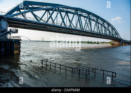 A view of a flooding area under a bridge. The persistent rain in southern Germany is causing a rise in the water levels in the Dutch area close to Germany. d. At the Gelderland border town of Lobith, a level of 12.85 meters above NAP (the base used to measure water levels) was measured. In Nijmegen, low parts of the quay, and around the harbor at the Waalkade are underwater. The water level of the Rhine reached a peak on Friday morning, but it was less high than initially expected. The expectation was that the water would rise to more than 13 meters above NAP. Stock Photo