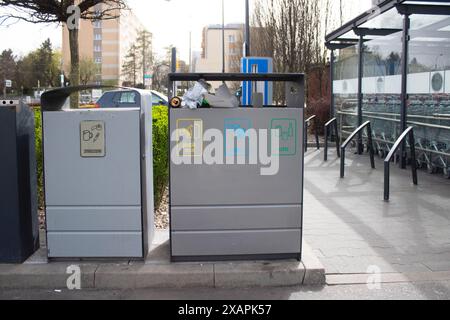 Public garbage bin with waste separation on a city street filled with garbage Stock Photo